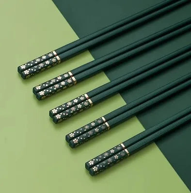 Set of green kawaii chopsticks with decorative ends on a green and beige background