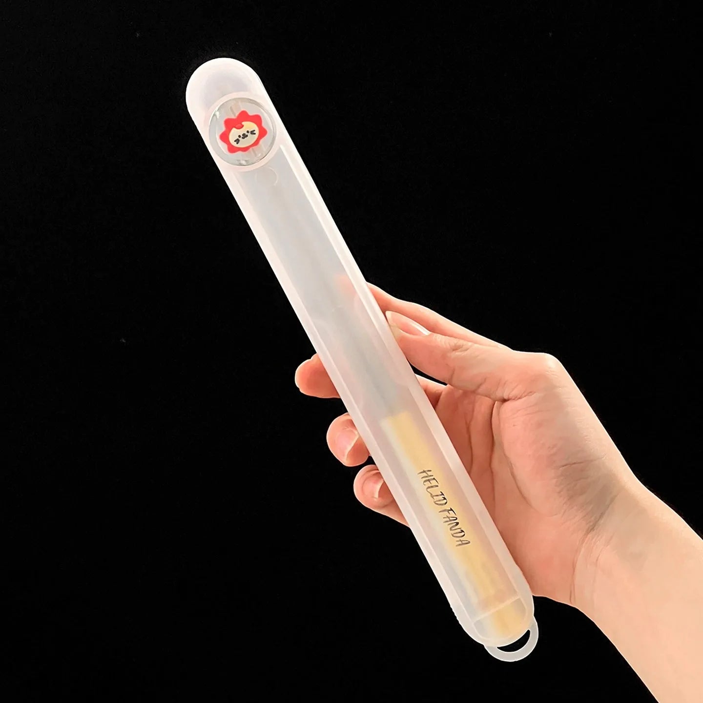 Hand holding kawaii chopsticks with a small cartoon character on a black background