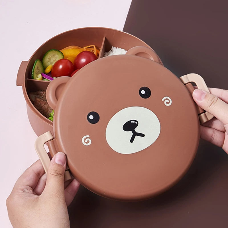 Bear-shaped kawaii lunch box with compartments filled with food on a pink background