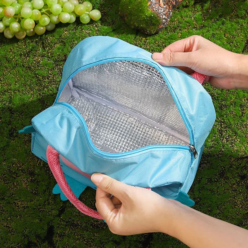 Blue insulated kawaii food bag with pink handle held by hands on a grassy background