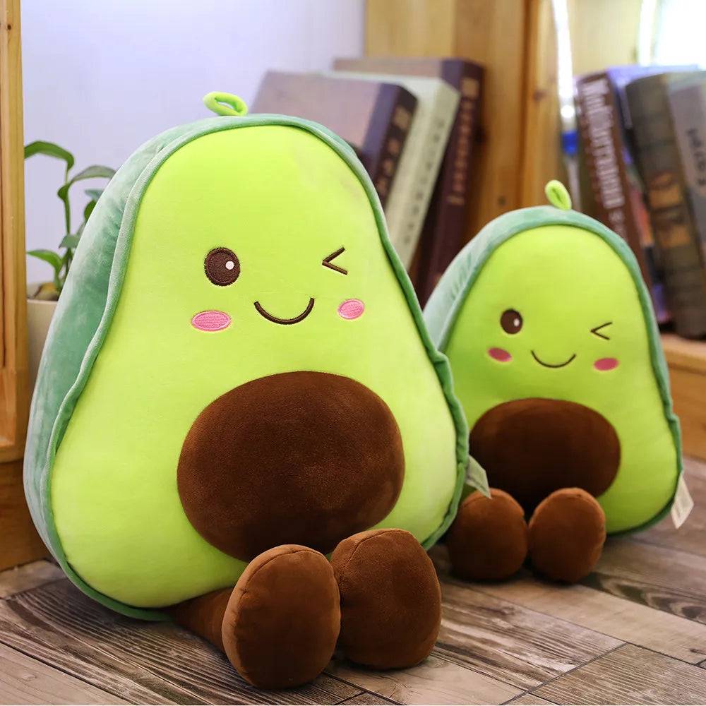Two kawaii plush avocado toys with smiling faces on a wooden surface.