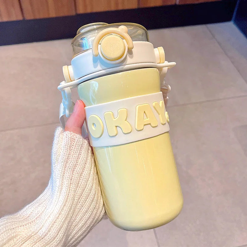 Pastel-colored kawaii water bottle with 'OKAY' text held by a person.