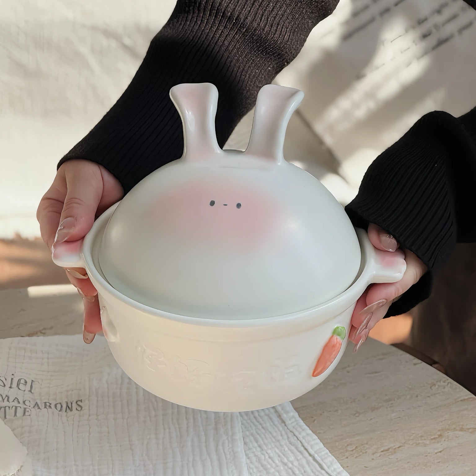 Person holding a cute ceramic kawaii bowl with rabbit design on a wooden surface.