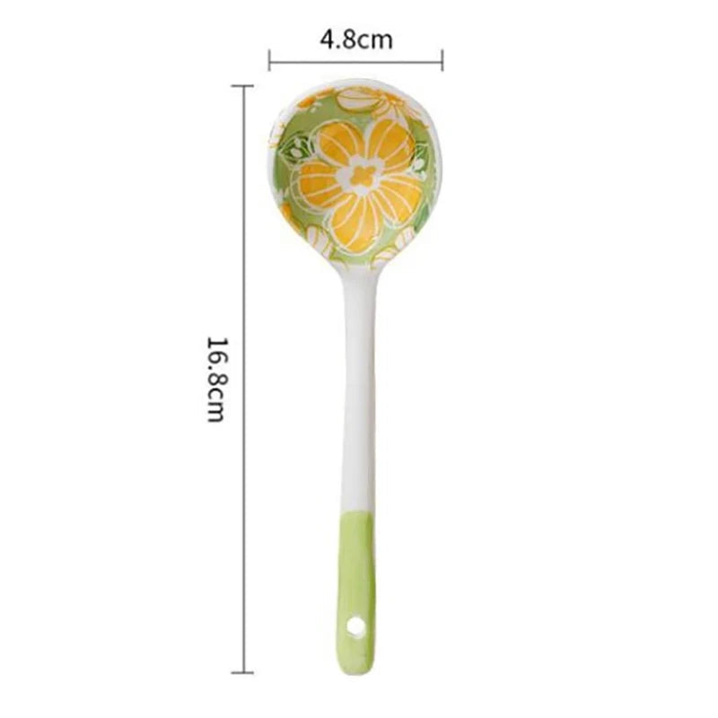 A green and yellow ceramic kawaii spoon on a white background