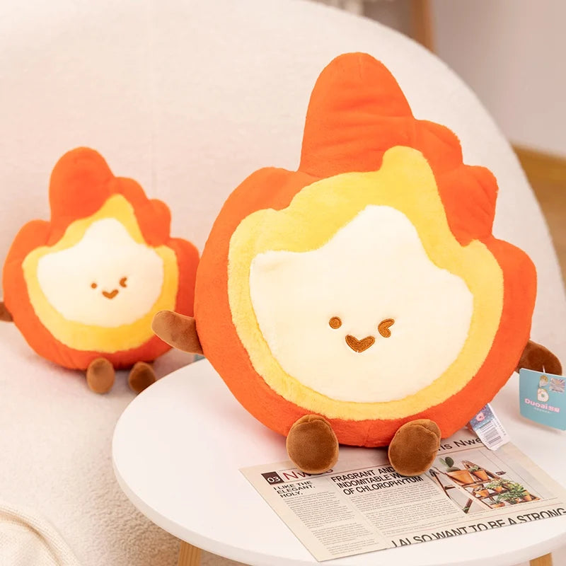 Two cute kawaii plush toys shaped like flames on a white surface with a newspaper underneath.