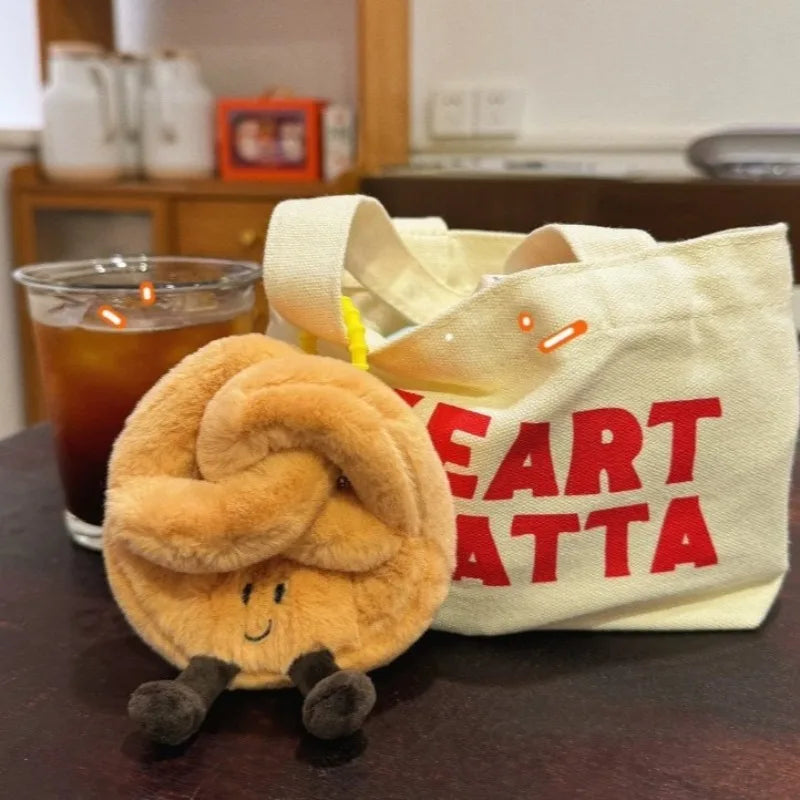 Plush kawaii bun toy next to a tote bag with text on a table.