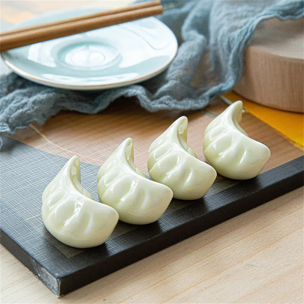 Four kawaii dumplings on a black tray with chopsticks and a white plate in the background.
