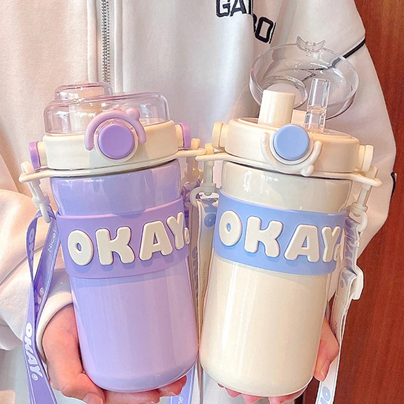 Two colorful kawaii water bottles with 'OKAY' straps held by a person.