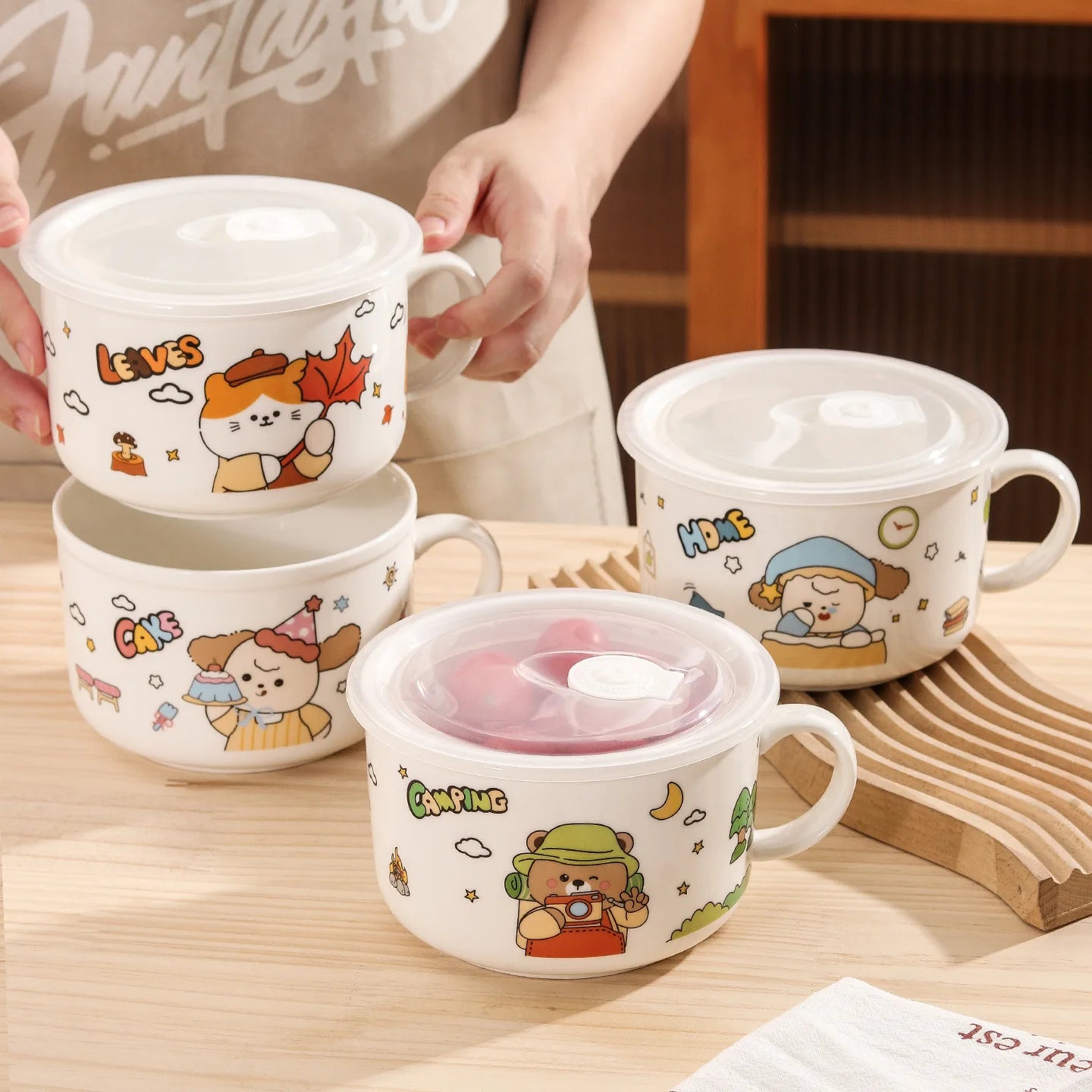 Set of cartoon-themed ceramic kawaii ramen bowls with lids on a wooden surface.
