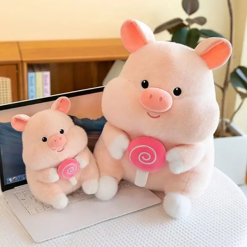 Two pink kawaii plush pigs with lollipop toys on a laptop