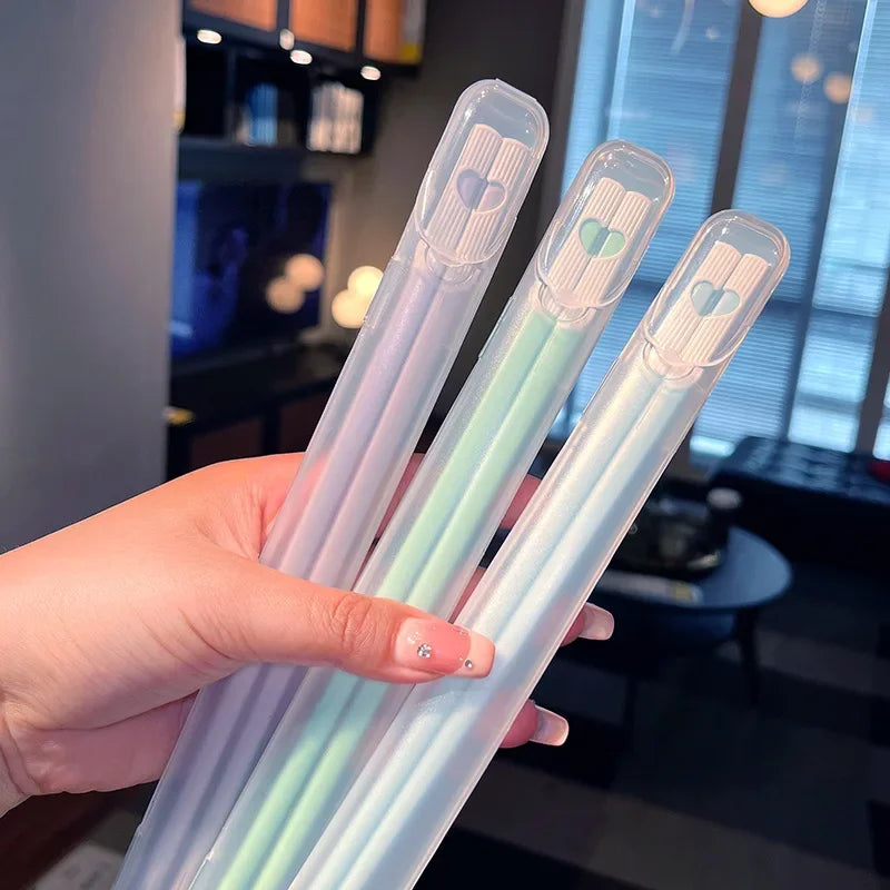 Hand holding four transparent kawaii chopsticks with colored tips in a kitchen setting