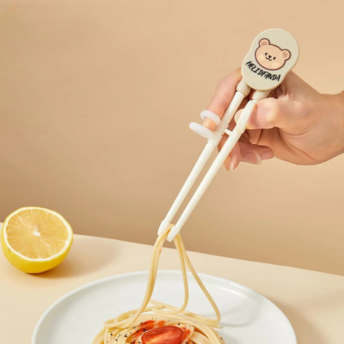 Cute bear-shaped kawaii utensils with a hand using it to lift spaghetti from a plate on a beige background.