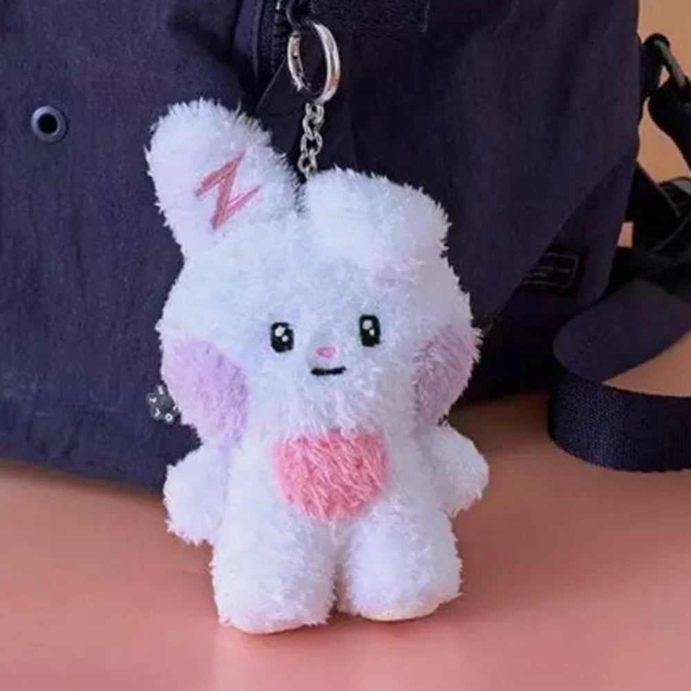 Plush kawaii keychain shaped like a white creature with pink accents, attached to a bag.