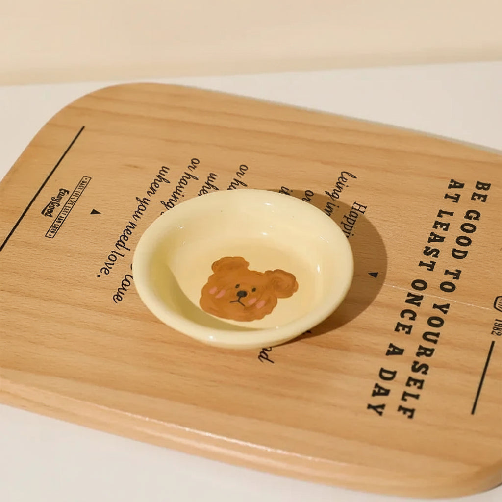 Small ceramic kawaii ramen dish with bear design on a wooden board with text
