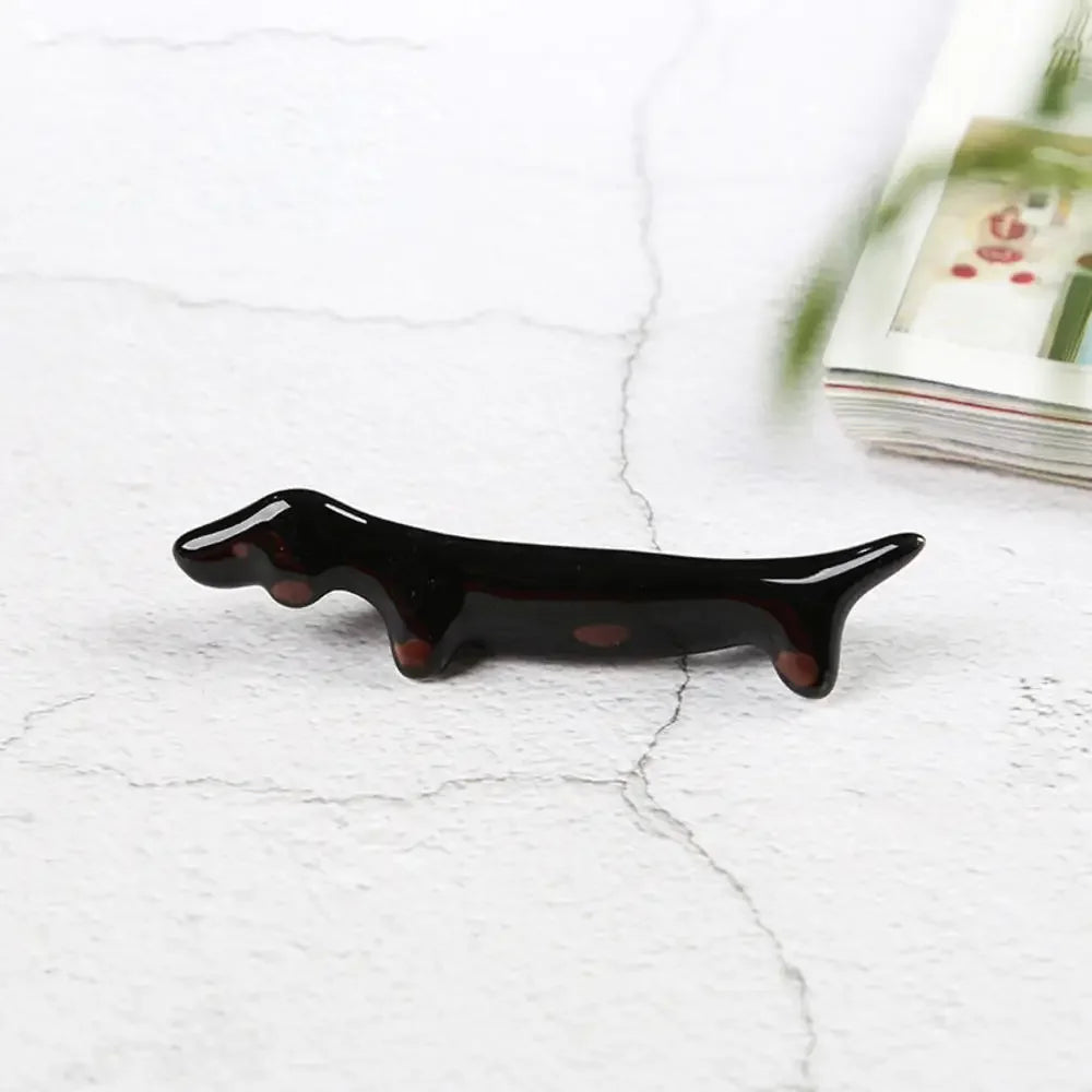 Black dog-shaped kawaii chopstick holders on a white marble surface