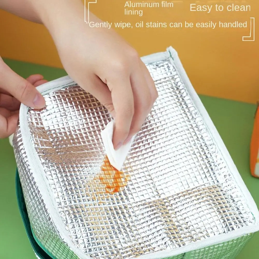 Person cleaning a metallic surface on a kawaii lunch bag with a cloth on a green background
