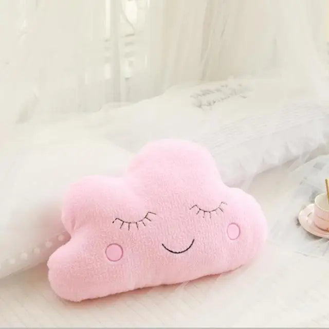 Pink cloud-shaped kawaii pillow with a smiley face on a light background
