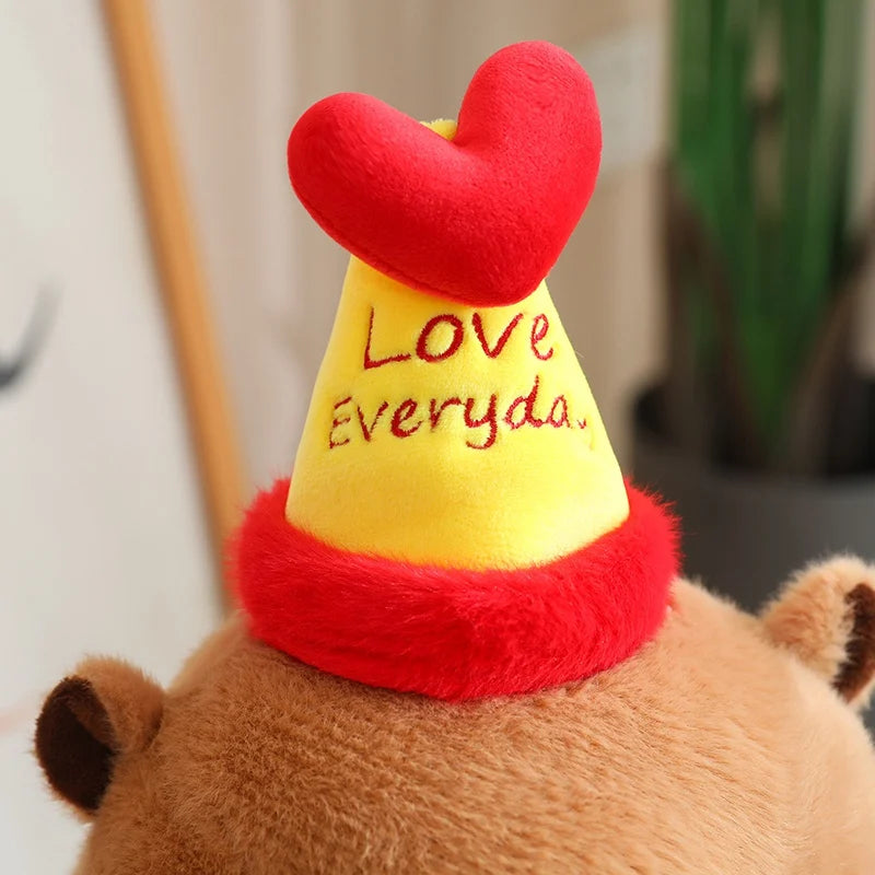 Capybara plush toy wearing a yellow cone hat with a red heart and 'Love Everyday' text.