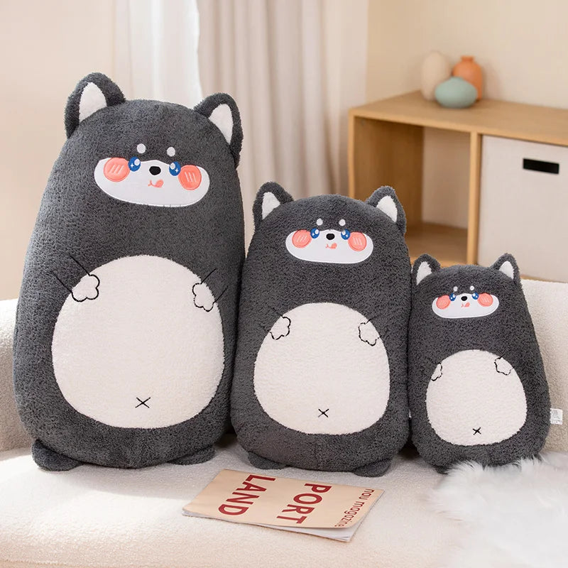 Three cartoonish gray kawaii plush toys with white faces on a light-colored couch.
