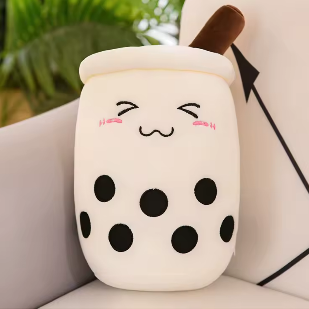 Kawaii plush toy shaped like a bubble tea cup with a face on a couch