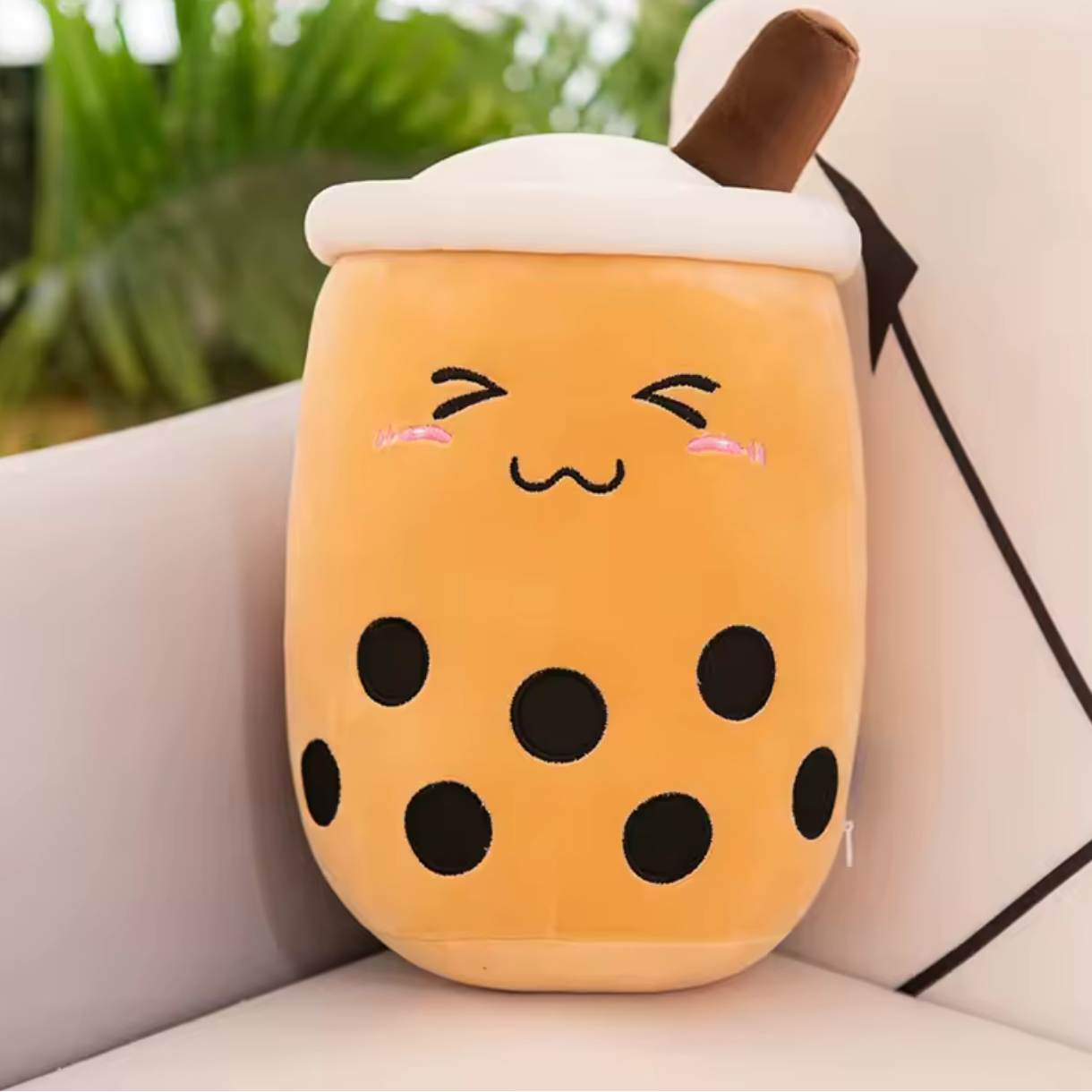 Kawaii plush toy shaped like a bubble tea cup with a face on a couch