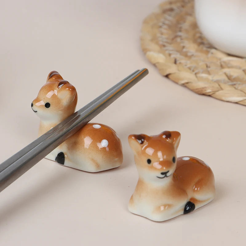 Two ceramic deer kawaii chopstick holders with a pair of chopsticks on a light background