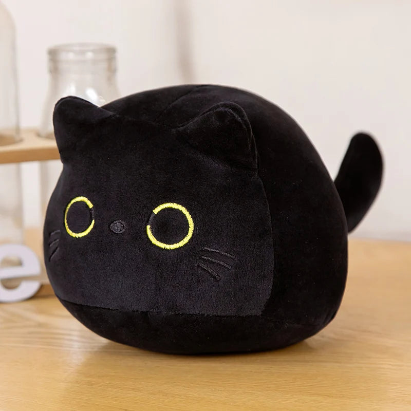 Black kawaii plush cat toy with yellow eyes on a wooden surface