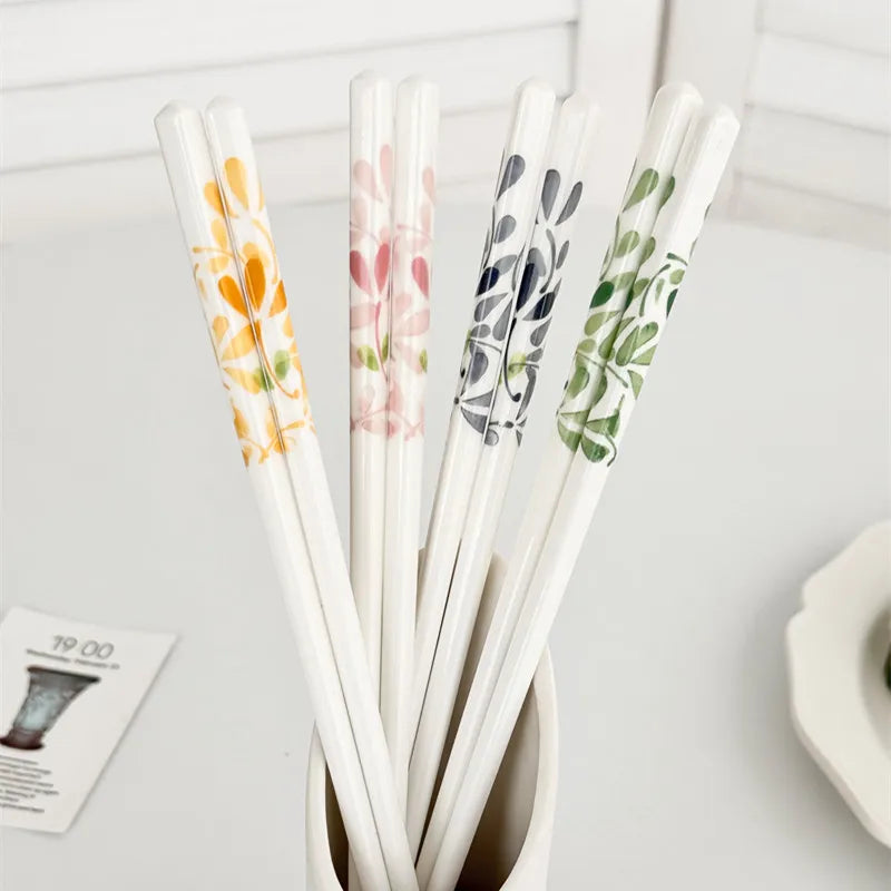 Set of floral-patterned kawaii chopsticks in a holder on a white surface