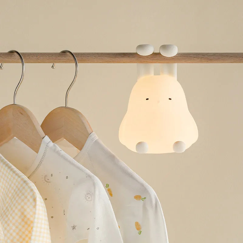Children's clothing on wooden hangers with a cute kawaii lamp fixture on a beige background