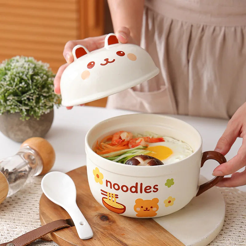 Ceramic kawaii ramen bowl with cartoon design on lid and side, containing noodles and vegetables, on a wooden cutting board.