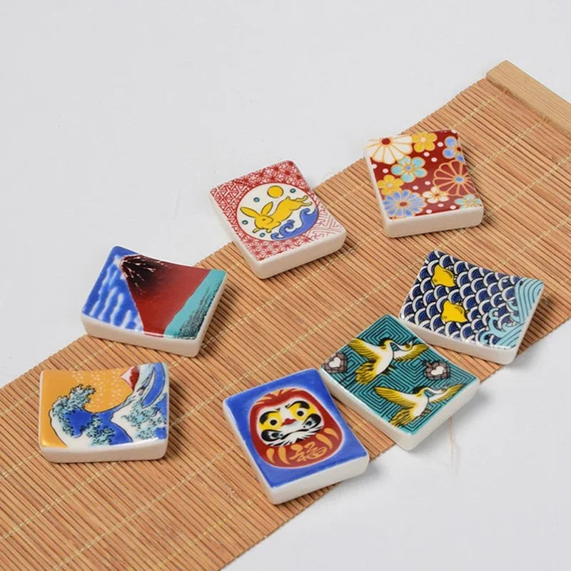 Set of colorful ceramic kawaii chopstick holders with various designs on a wooden surface.
