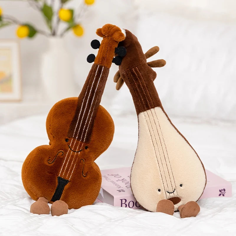 Two kawaii plush toys shaped like a violin and a lyre on a white surface with a blurred background.