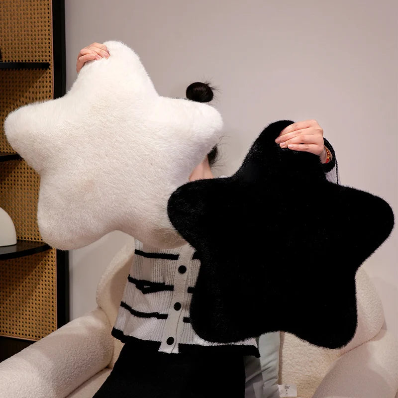 Person holding a large white star-shaped pillow against a neutral background