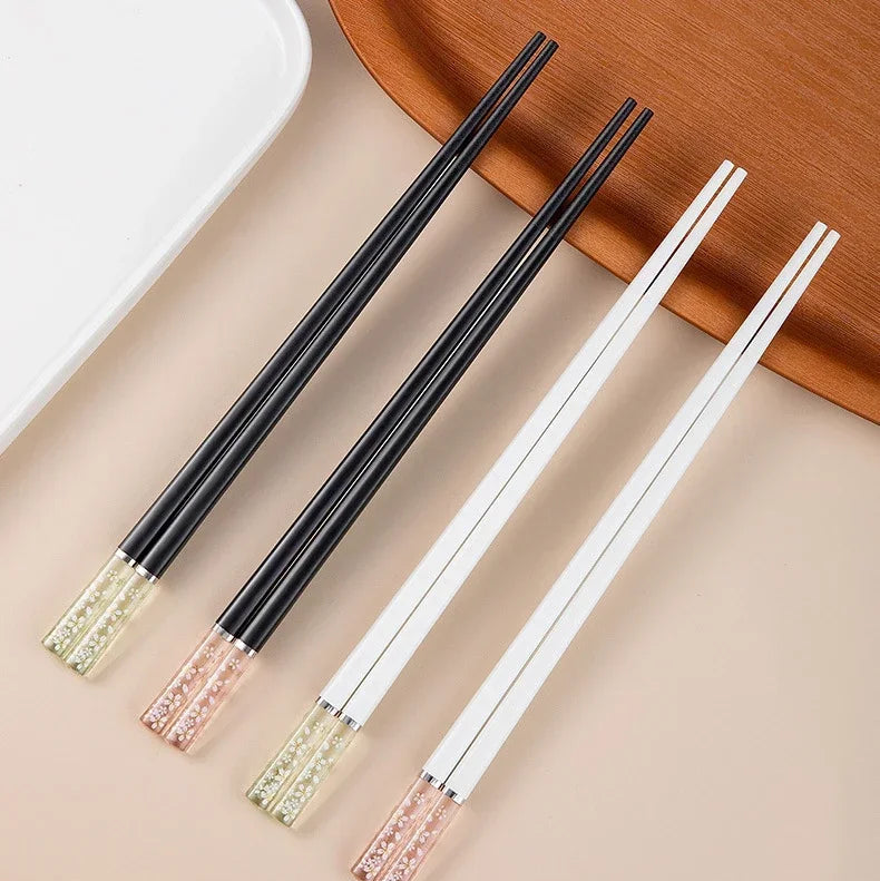 Set of black and white kawaii chopsticks with decorative tips on a beige surface.