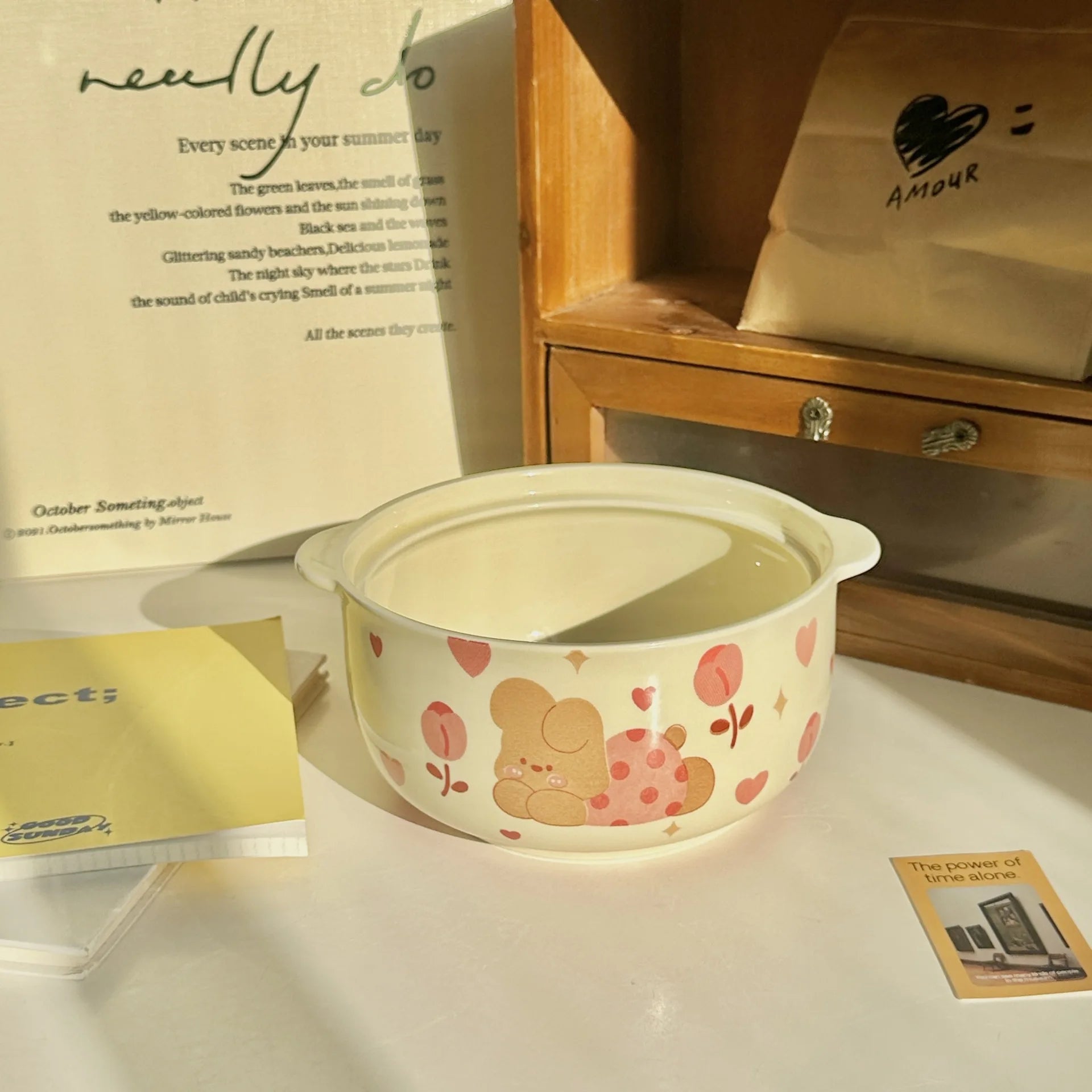 Ceramic kawaii ramen bowl with cartoon design on a surface with books and a bag in the background
