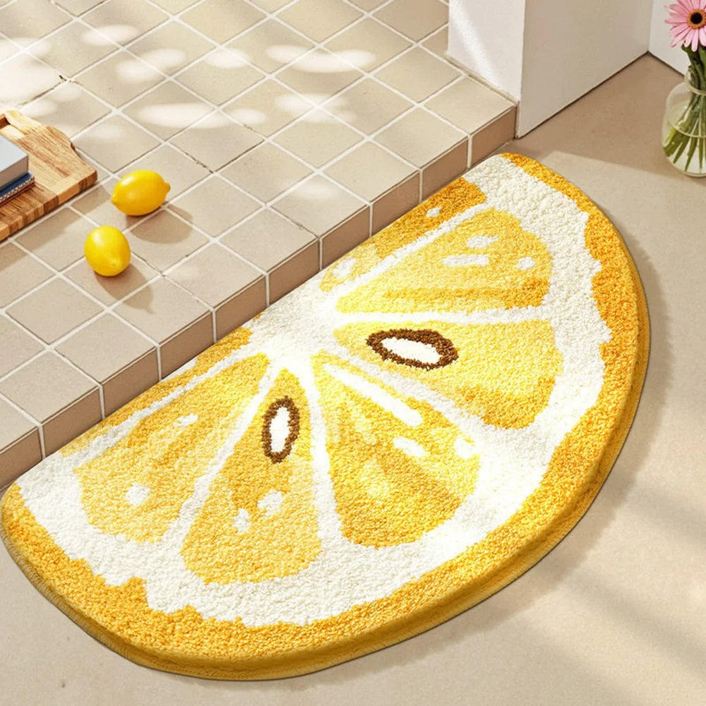 Round lemon-shaped kawaii bath mat on a bathroom floor with tiles and a small plant in the background.