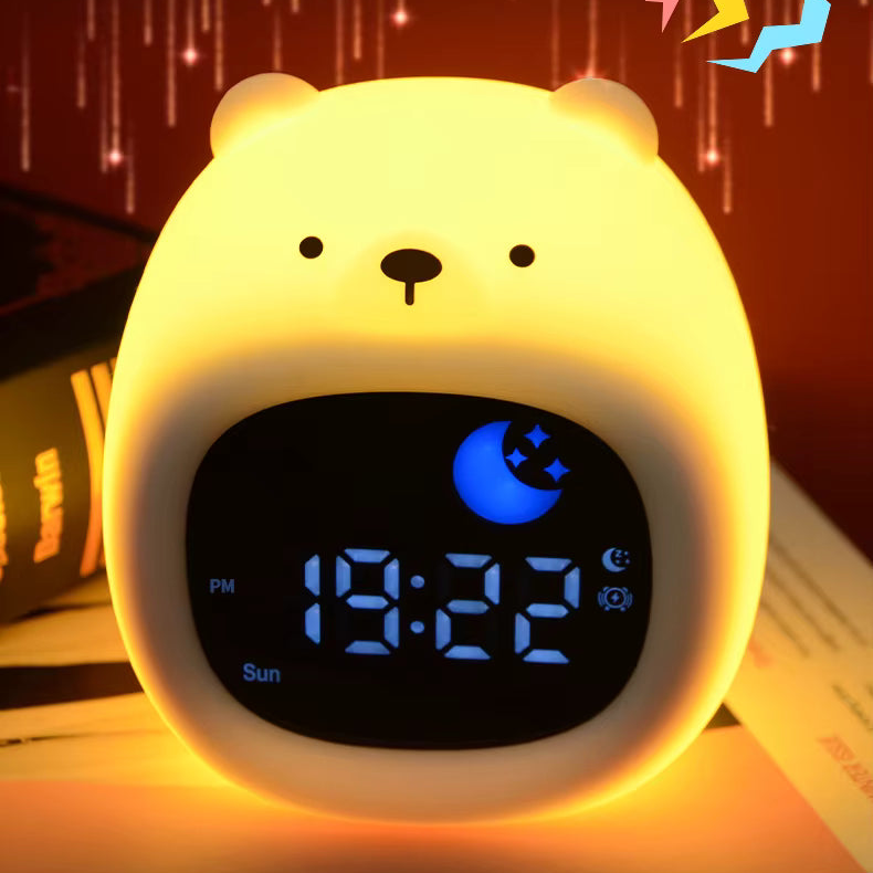 A cute bear-shaped digital alarm clock glowing with warm yellow light. The clock has a rounded body, simple black facial features, and a digital display showing 19:22 with a blue moon icon.