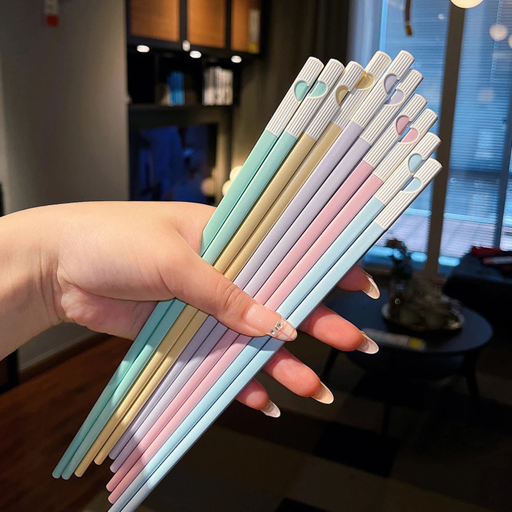 Hand holding colorful kawaii chopsticks in a kitchen setting