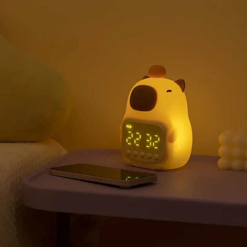Yellow cartoon-style kawaii alarm clock on a nightstand with a smartphone next to it, in a dimly lit room.