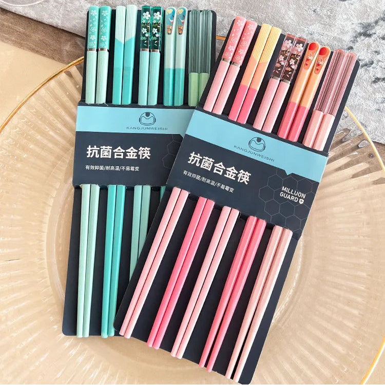 Two sets of colorful kawaii chopsticks in packaging on a textured surface