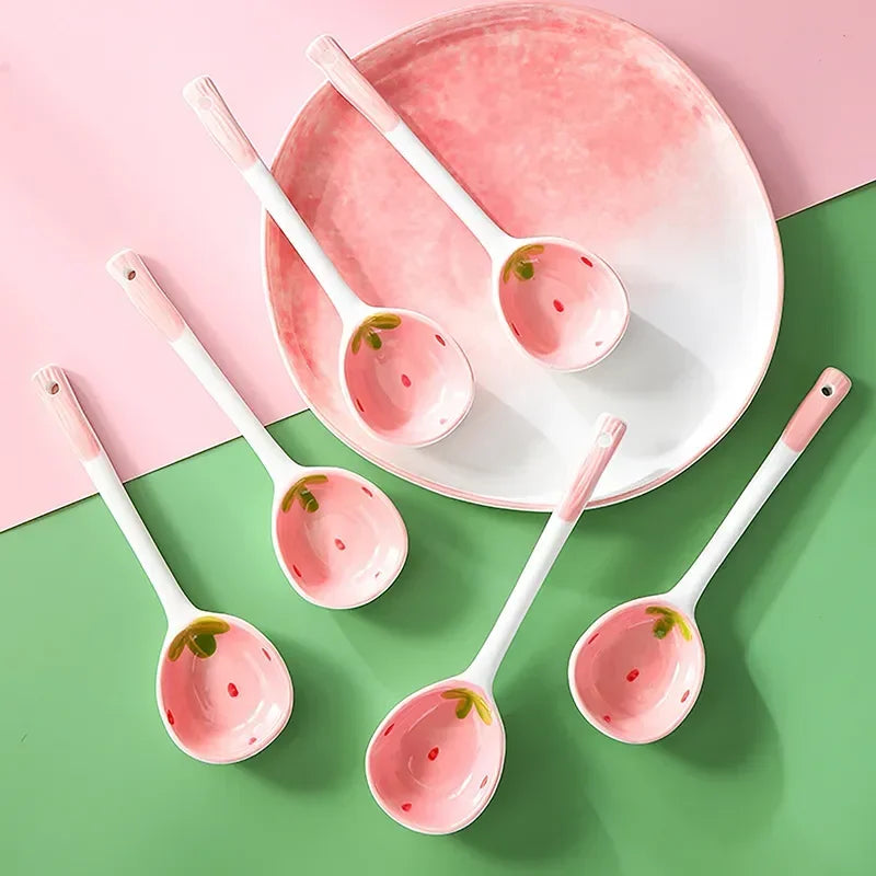 Set of ceramic kawaii spoons with strawberry design on a pink and green background