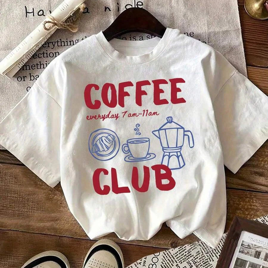 White t-shirt with 'Coffee Club' text and kawaii graphics on a wooden surface.