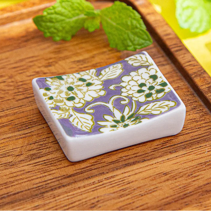 Small rectangular ceramic kawaii chopstick holders with floral design on a wooden surface