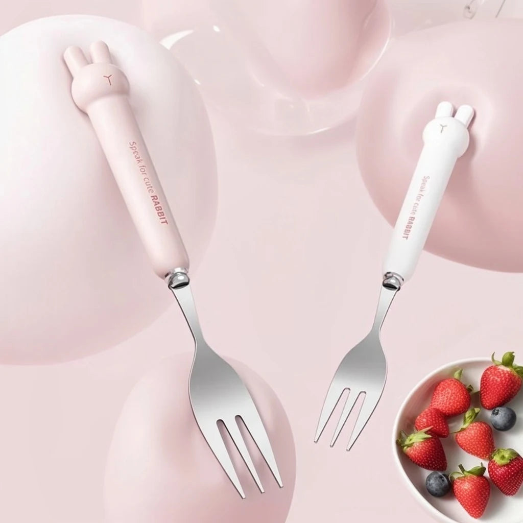 Two pink-handled kawaii utensils with cat-shaped handles on a pink background with strawberries.