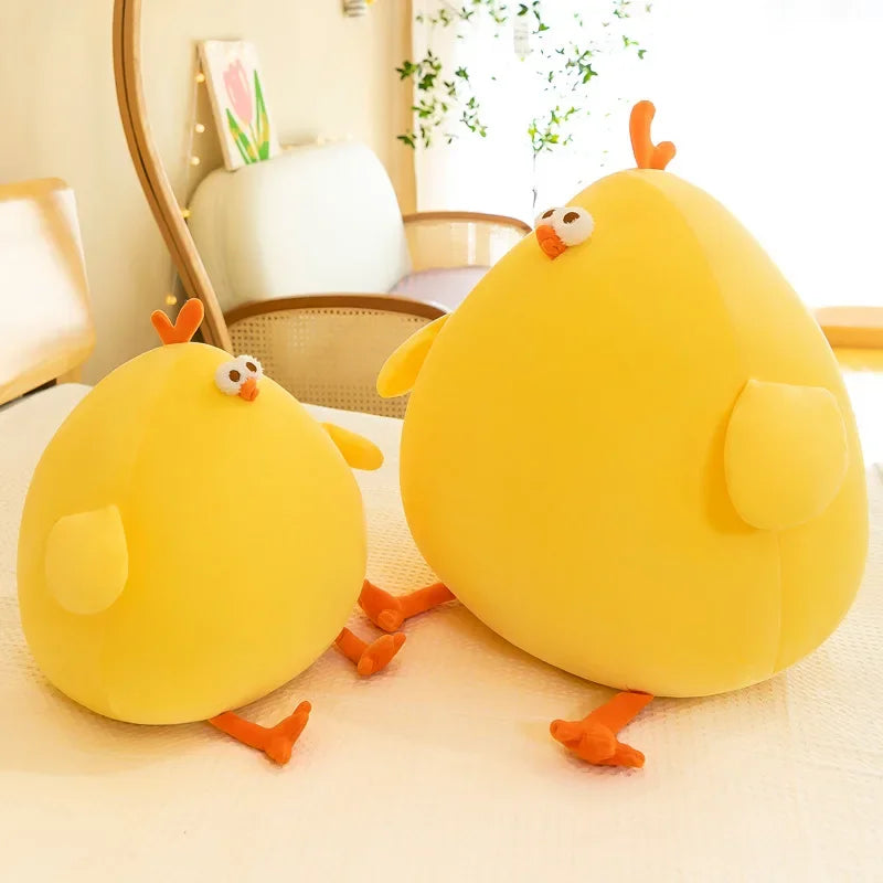 Two yellow chick-shaped kawaii cushions on a light-colored surface with a blurred indoor background.