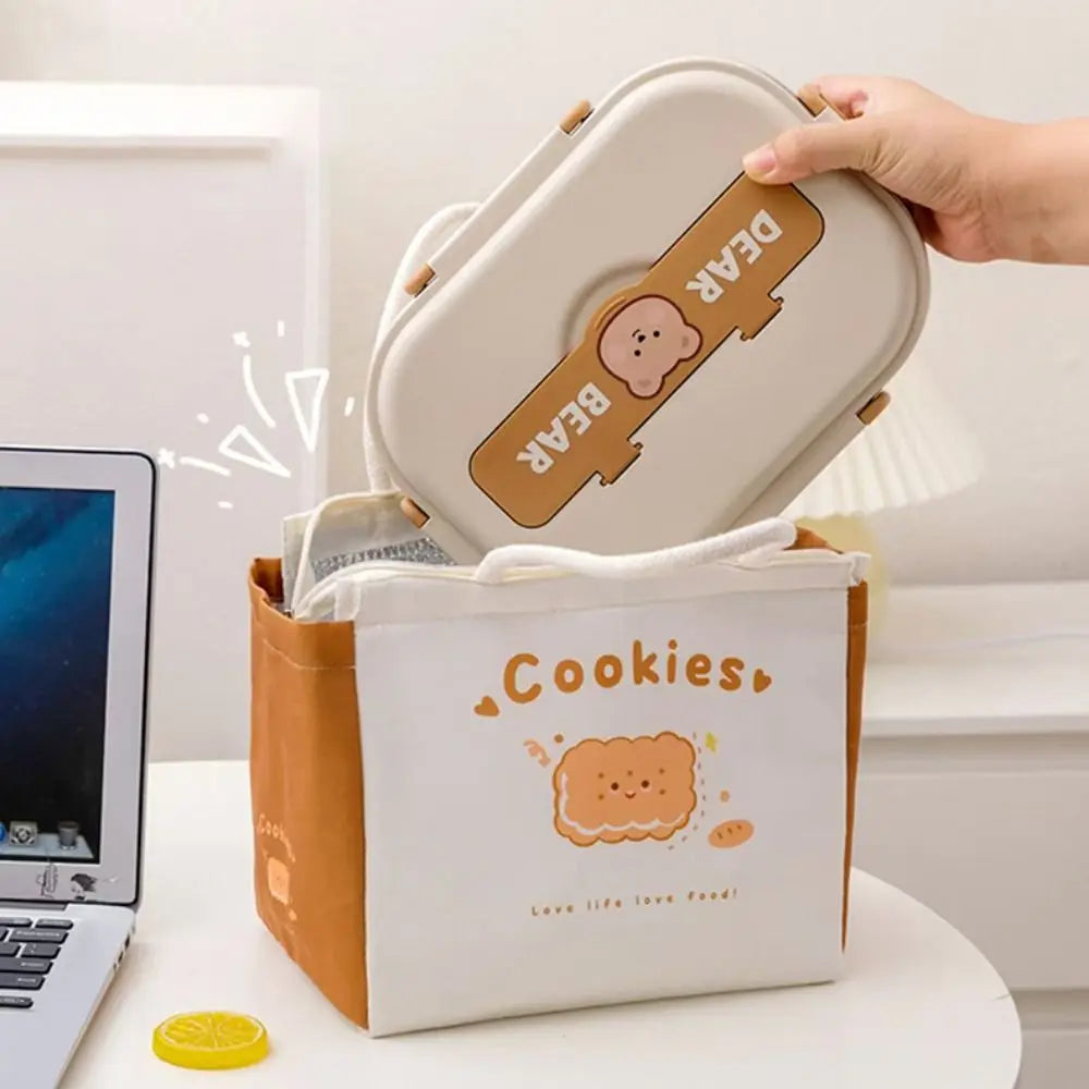 Kawaii lunch bag with a bear design being opened by a hand, laptop in the background