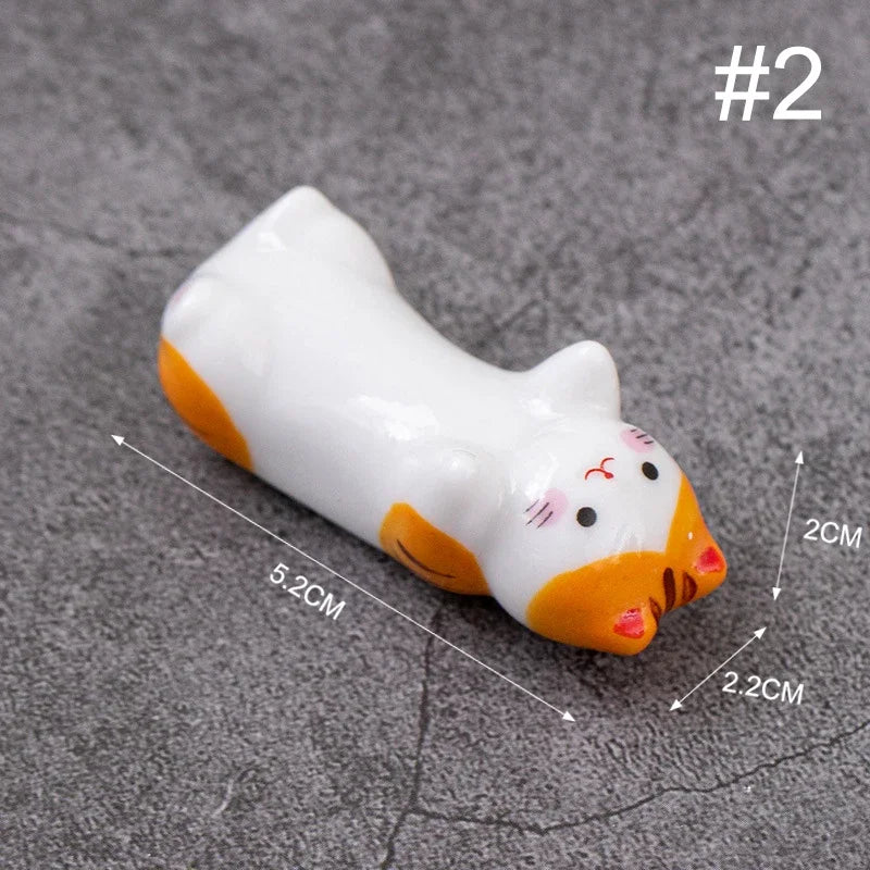 White and orange cat-shaped kawaii chopstick holders with measurements on a gray background