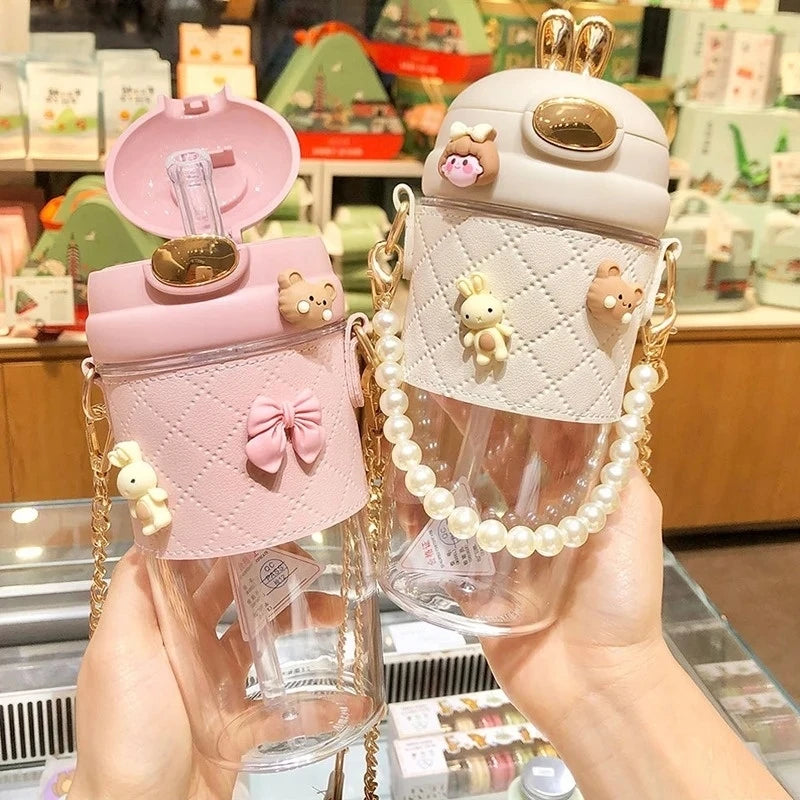 Two cute kawaii water bottles with bear decorations held in a store setting.