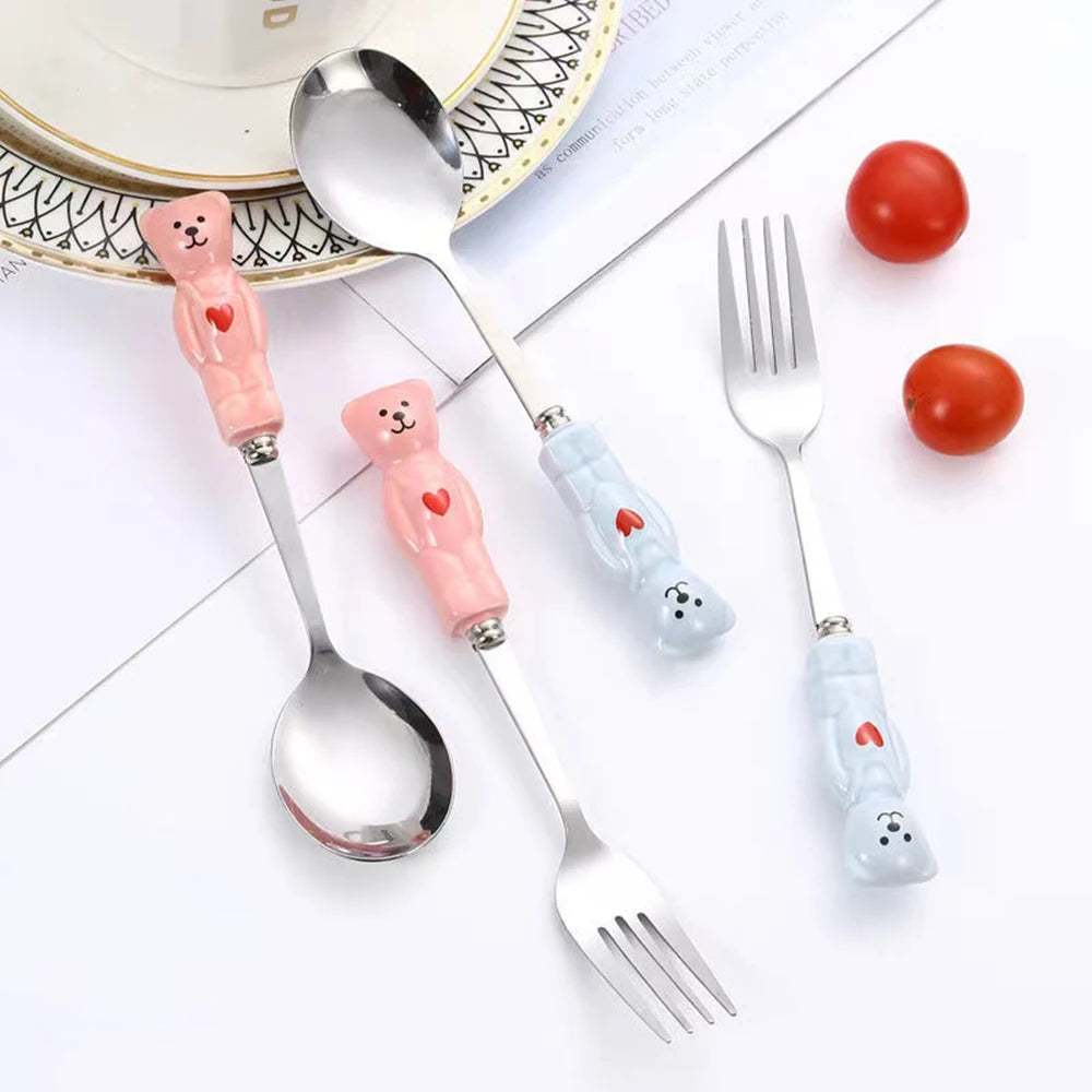 Set of kawaii utensils with bear handles on a white surface with tomatoes.