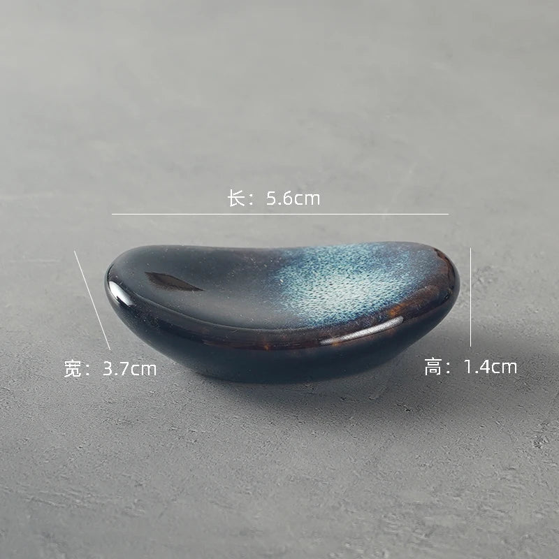 Black ceramic kawaii chopstick holders with dimensions on a gray background